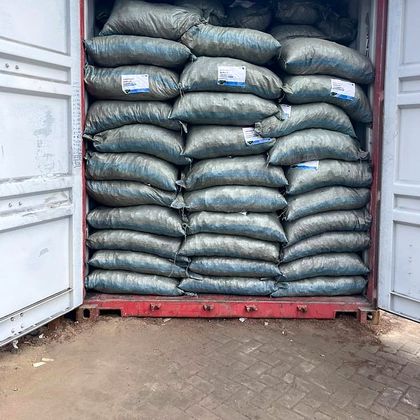 A shipping container packed wall to wall with labelled sacks of coconut shell charcoal.