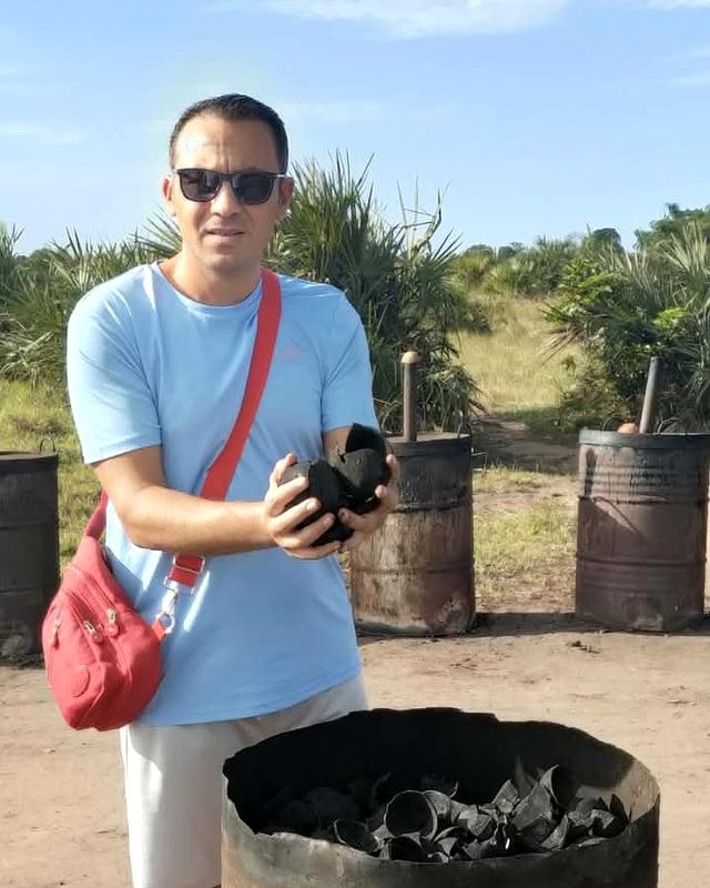 Miqdad Ghaith, Export Manager, standing beside the drum kilns holding a piece of carbonized coconut shell.